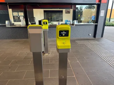 A yellow myki reader at Coburg station — when the screen says 'Tap below', hold your card or phone against the pad underneath