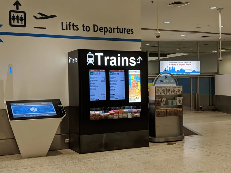 The train information point inside T1 (International): next departures, stops and platform numbers.