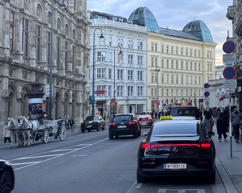 A taxi stopped at the kerb in central Vienna, carrying the yellow TAXI roof sign.