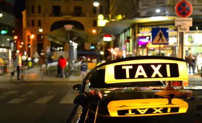 The illuminated TAXI roof sign at night.