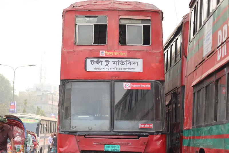 Destinations are written on a board across the front, in Bengali. This state-run BRTC double-decker reads "Tongi to Motijheel" on the board, with a special-event service notice on the windscreen.