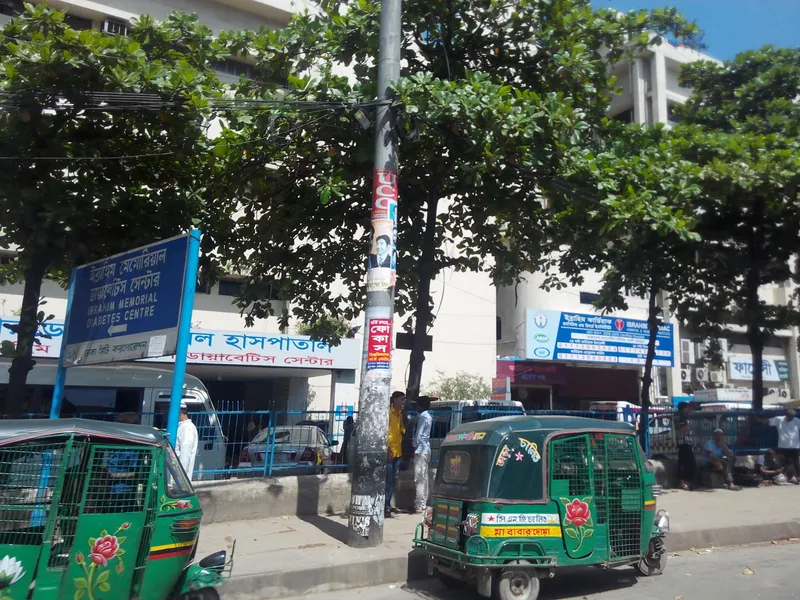 A green CNG auto-rickshaw — mesh sides, and a band on the body reading "CNG-powered" in Bengali.
