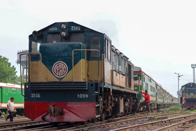 A Bangladesh Railway locomotive (No. 2506) and its green coaches in a Dhaka station yard