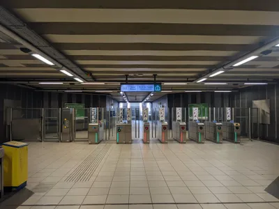 The fare gates — tap on the blue-lit pad on top of the pedestal. Only the aisles showing a green arrow are open.