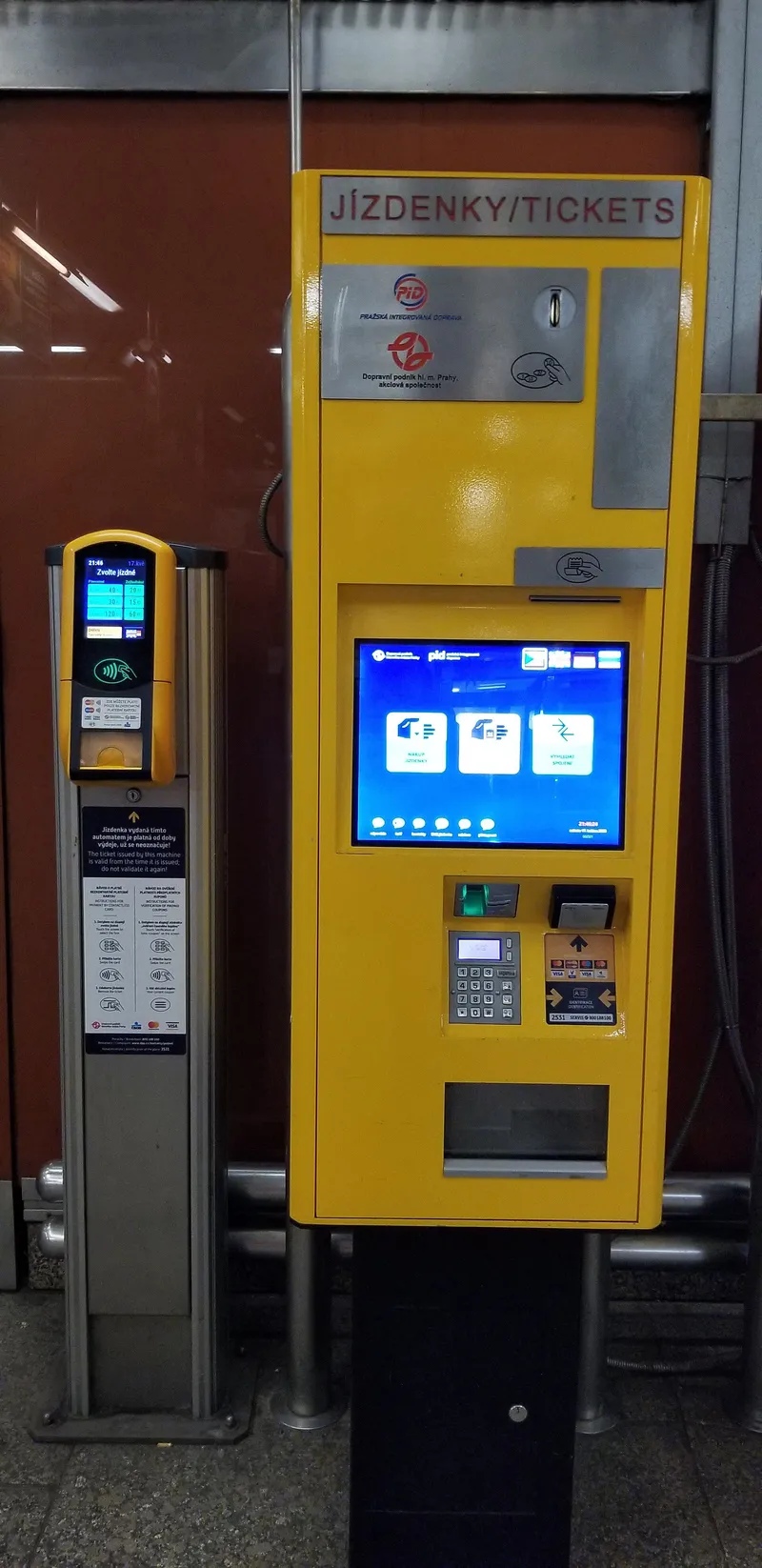 Two machines side by side in the vestibule: the tall yellow JÍZDENKY/TICKETS machine takes coins and cards, while the slim terminal on the left is contactless-card only