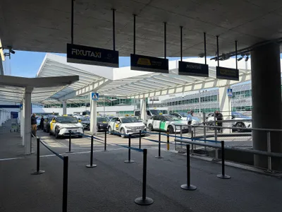 The taxi rank on the arrivals level — the four contracted companies each have their own lane under their own sign.