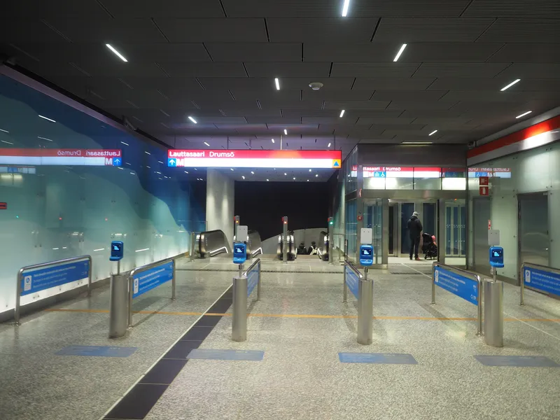 Lauttasaari station: past the blue card readers on the posts you are inside the paid zone, and the floor decal states the €100 penalty fare.