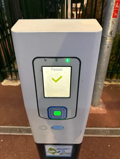 A free-standing validator at a suburban Transilien station (Champagne-sur-Oise) — tap the reader below the screen and it answers "Passez" with a green tick.