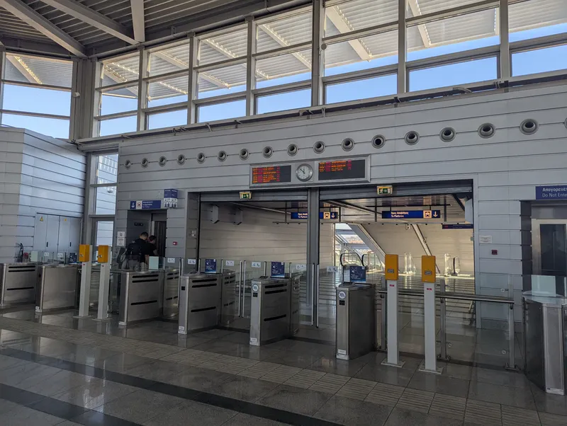 The metro gates at the airport station — the blue panel beside them reads "Travel with your bank card as your ticket"
