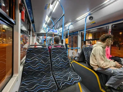 夜行バスの車内。乗降口脇の青いポールに、緑の表示窓が付いたオレンジの刻印機がある