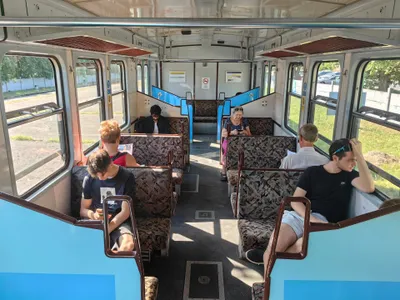 Inside an H5 HÉV car - an older vehicle with facing seats and a narrow wooden luggage rack above the windows.