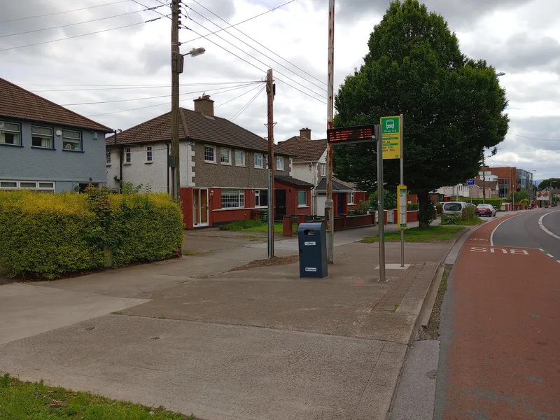 The stop flag carries the stop number, its name and the routes by operator, and the LED sign beside it counts down the minutes to the next buses.