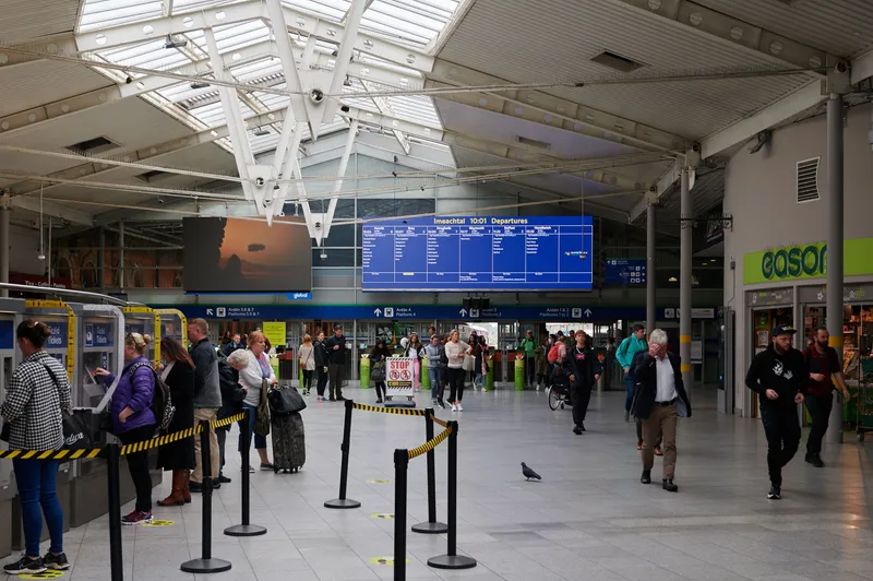 The concourse at Dublin Connolly: the row of machines on the left is marked 'Ticeid / Tickets', with the fare gates and the blue departure board straight ahead.