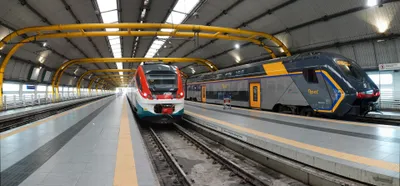 Two kinds of train side by side at the airport station — the Hitachi "Rock" on the right is a regional (REGIONALE) service to Roma Ostiense