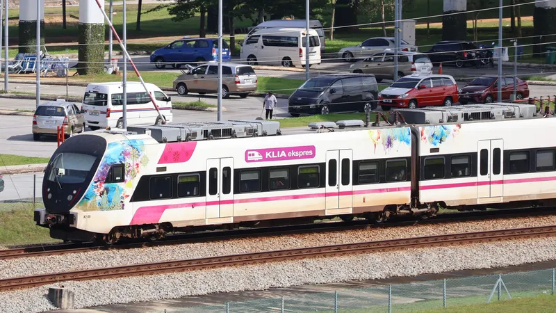 A KLIA Ekspres train beside KLIA Terminal 2 — a side logo reading KLIA ekspres means the non-stop service