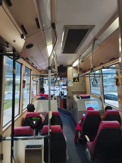 A card reader on an aisle pole inside a Rapid KL bus — a red tOUCH sits above a lit tap-your-card pictogram