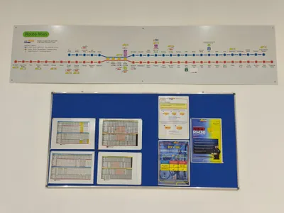 A KTM Komuter notice board (Segambut Utara) — route map on top, printed timetables pinned below. Trains are sparse, so read the return times off this board at whichever station you get off