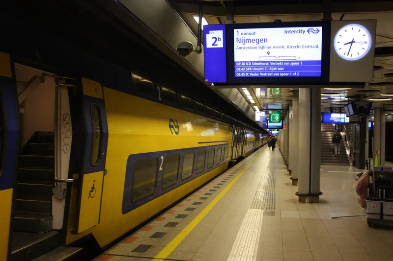 A departure board at Schiphol: minutes to departure, the type of train, its destination and the main stops it calls at. The train shown is heading towards Utrecht, not Amsterdam Centraal.