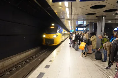 The station sits directly beneath the terminal - travellers wait on the platform with their suitcases in hand.