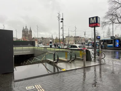 The metro entrance on the square in front of Amsterdam Centraal; the blue "M" sign marks the way down.