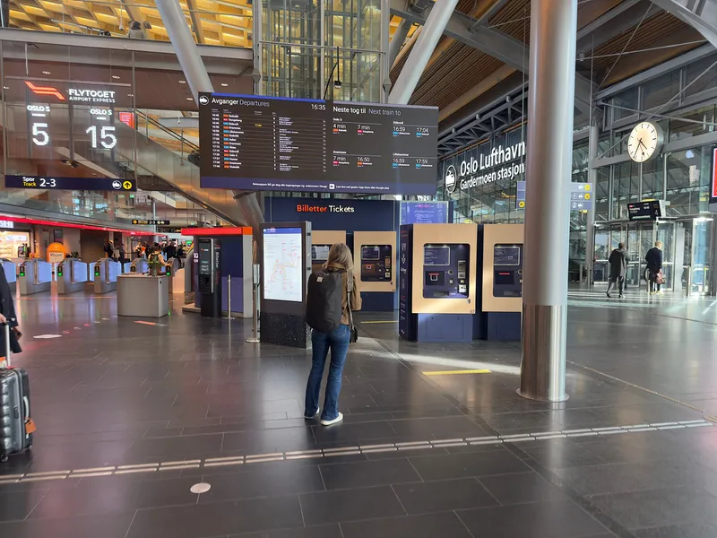 The concourse at the airport station. On the left are the gates to the Flytoget platforms (tracks 2-3): you can tap a card on the reader there instead of buying a ticket. The machines under "Billetter Tickets" in the centre are Entur's, selling tickets for Vy, SJ and Go-Ahead.