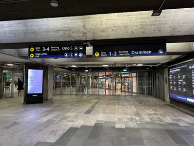 Signs at the underground station point by direction: "Track 3-4 - towards Oslo S" (the airport symbol sits alongside) and "Track 1-2 - towards Drammen".