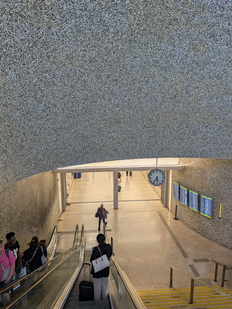 Aeroporto metro station at the airport. Flight information screens line the wall and travellers wheel their suitcases straight down the escalators to the platforms.