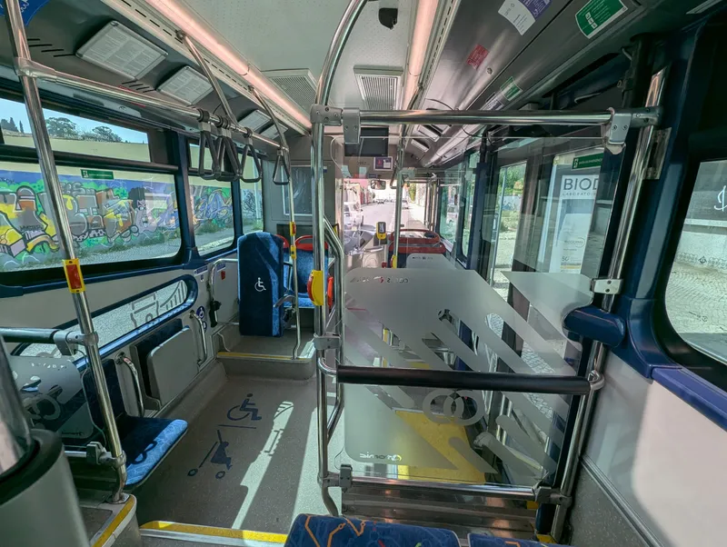 Inside a Carris bus. The yellow validator stands on a post beside the driver's cab - this is where you tap when you board.