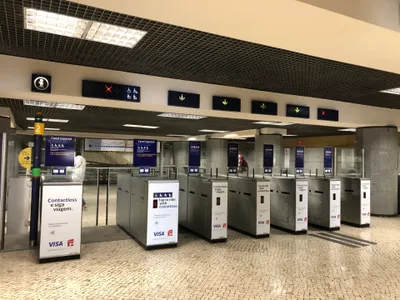 Fare gates at Restauradores. The gates are marked "Contactless e siga viagem / Tap to ride with contactless", and a green-bordered sticker on the glass above reads "Passe o cartao, nao a carteira - tap your card, not your wallet".