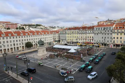 The taxi rank on Praca da Figueira. Black with a turquoise roof is one of the licensed liveries - plain cream-beige cars are licensed taxis too - so identify them by the roof sign and the meter.