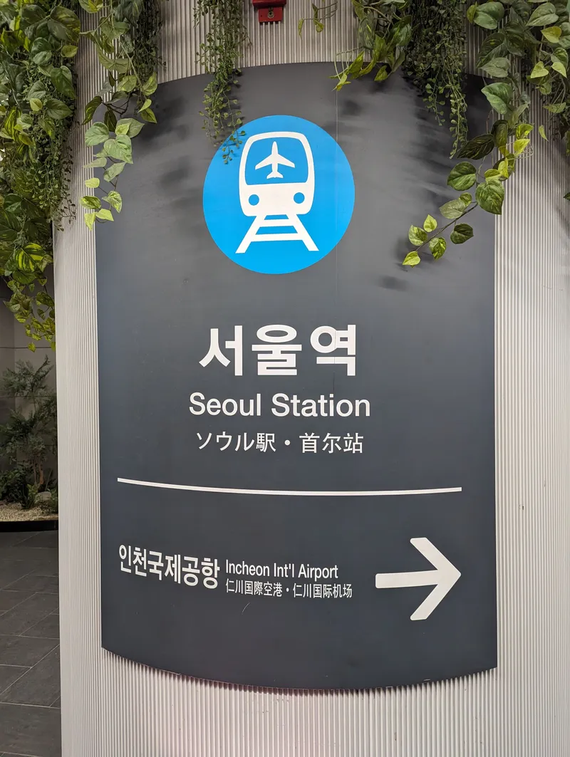 The airport railway (AREX) sign at Seoul Station: the station name in Korean, English, Japanese and Chinese, with an arrow to Incheon Int'l Airport below.