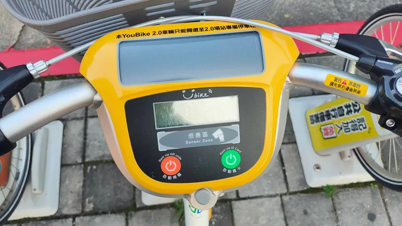 The panel on a YouBike 2.0's handlebar — orange unlocks by QR code, green by IC card