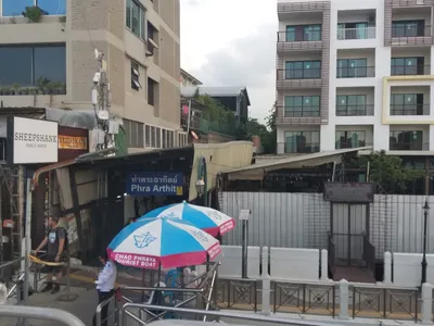 A pier entrance — the blue board gives the pier name; the parasols belong to the blue-flag Tourist Boat