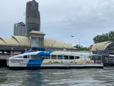 A Tourist Boat at Sathorn Pier — a blue flag at the stern, “HOP ON HOP OFF” on the hull
