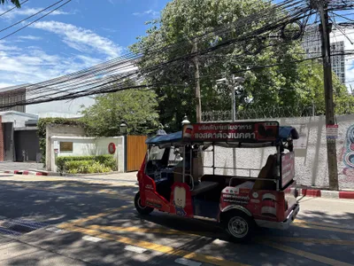 A MuvMi electric tuk-tuk — the side panel carries the mascot and the app-store badges