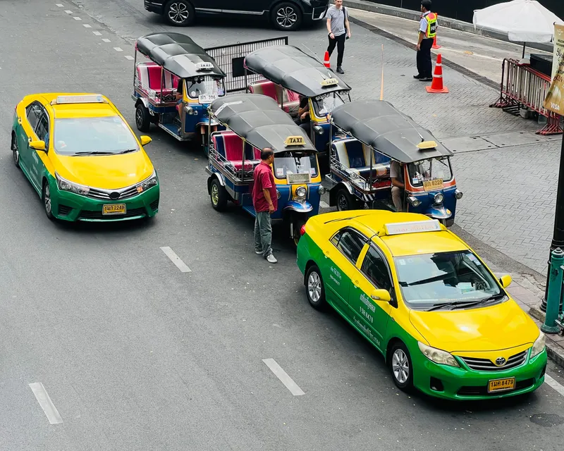 Tuk-tuks waiting for fares — look for the TAXI roof sign and the yellow plate