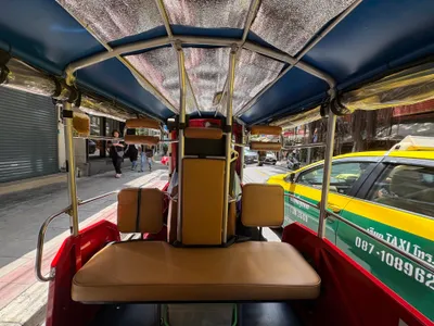 From the passenger bench of a tuk-tuk — open sides, just a canvas roof