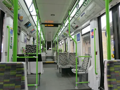 Inside the tram — the pillar notice reads '£100 penalty fare', so tap on the platform before you board
