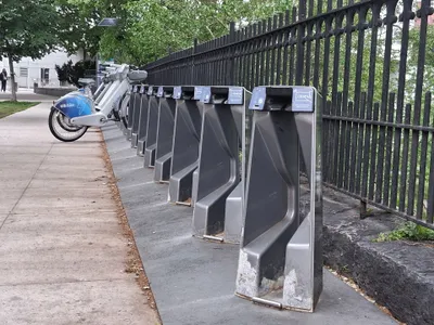 A Citi Bike station: a row of empty docks, with e-bikes docked at the far end