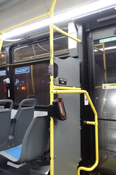 OMNY reader by the rear door of a local bus — the red screen reads ENTER FRONT DOOR