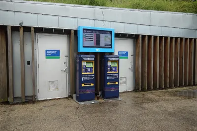 Two NYC Ferry ticket machines at a landing, with the next-departure screen above