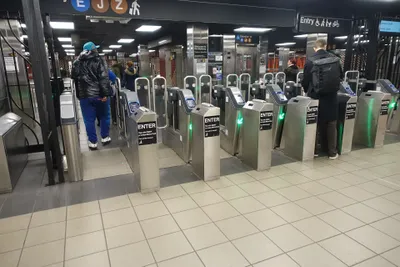 A bank of subway turnstiles; the ENTER placards and green arrows mark the lanes you can enter through