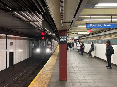 A J train arriving at Fulton Street — routes are shown as a number or letter inside a coloured circle