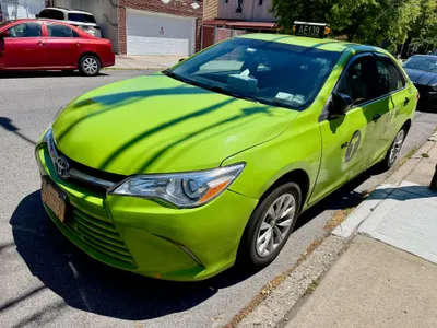 A green Boro Taxi — number light on the roof and the round "NYC T BORO" emblem on the door