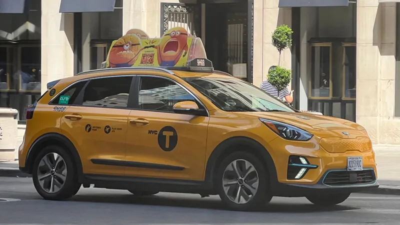 A yellow medallion cab — number light on the roof, the black NYC "T" emblem and medallion number on the door