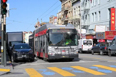 An articulated Muni trolleybus in Chinatown — the poles on the roof draw power from the overhead wires
