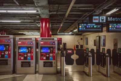 Muni Metro fare gates at Powell station — tap at the black paddle gates to enter; the station's ticket machines stand to the left